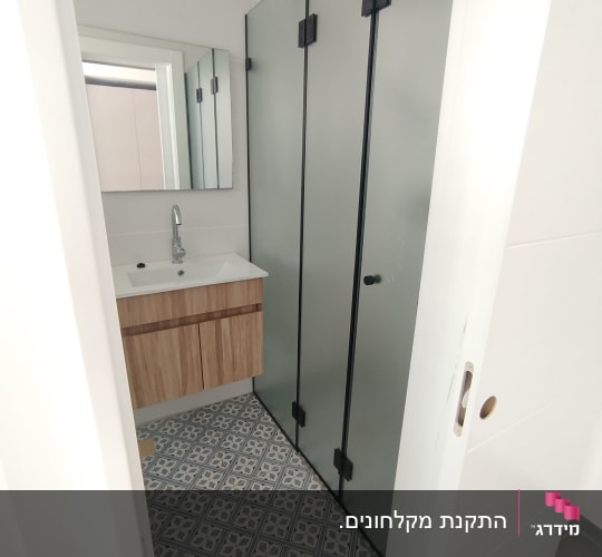 חדר אמבטיה עם מקלחון ודלת זכוכית